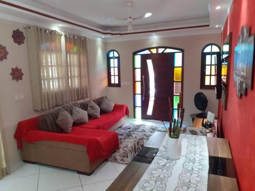 uma sala de estar com um sofá vermelho e algumas janelas em Casa Condomínio Morada da Praia -Praia Boracéia SP em Bertioga