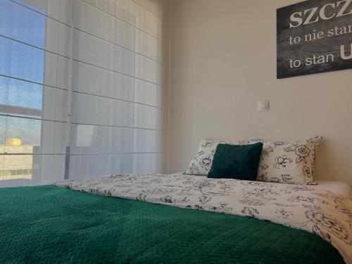 ein Schlafzimmer mit einem Bett mit einer grünen Decke in der Unterkunft Parkcity Sokolska in Kattowitz