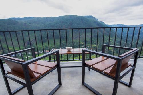 a balcony with two chairs and a table with a view at Dowa Elegance Resort in Ella