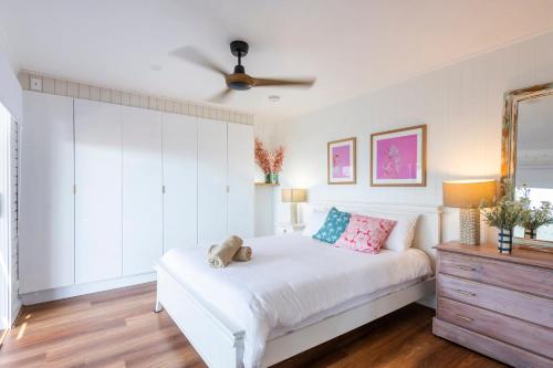 a bedroom with a white bed and a ceiling fan at Bimbajong Studio - oceanstays in Yamba