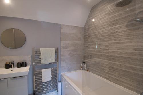 a bathroom with a tub and a sink and a mirror at 6 Bedroom Holiday Home with Hot Tub & Garden in Luton