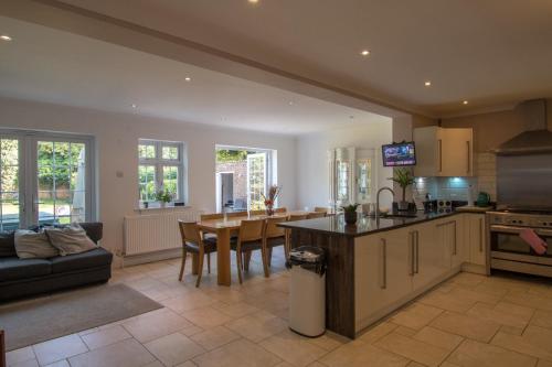 een keuken en een woonkamer met een bank en een tafel bij 6 Bedroom Holiday Home with Hot Tub & Garden in Luton