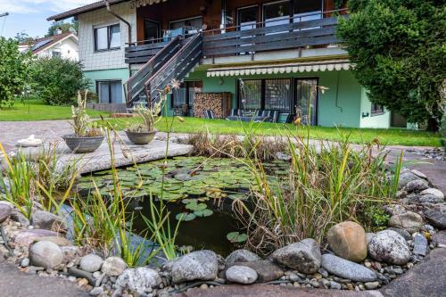 un jardin avec un étang en face d'une maison dans l'établissement Haus Berger, à Wehr