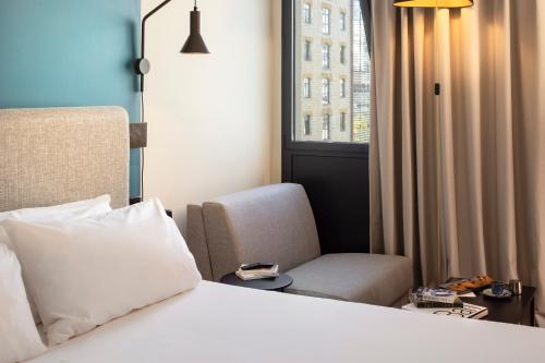 a bedroom with a bed and a chair and a window at ibis Marseille Centre Euromed in Marseille