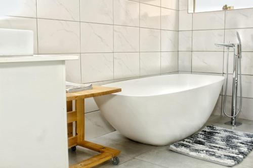 a white bath tub in a bathroom with a table at Mills Pad with 2-bedroom in Nelspruit