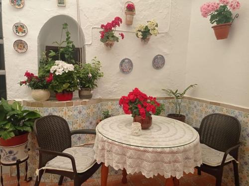 un tavolo con sedie con fiori e piatti appesi a un muro di Casa típica de pueblo andaluz a Villanueva de San Juan