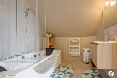 a bathroom with a tub and a sink at Les Volets Bleus in Dornes