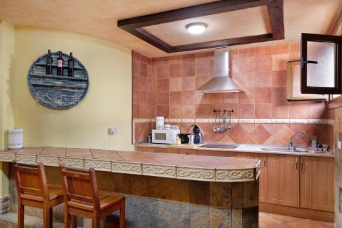 a kitchen with a counter with chairs and a microwave at Casa Barriguita in Yaiza