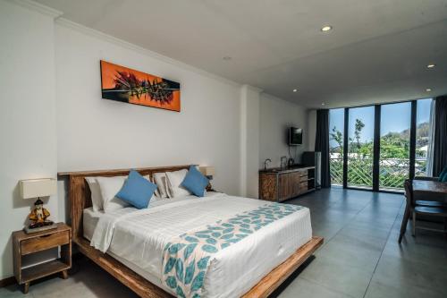 ein Schlafzimmer mit einem großen Bett mit blauen Kissen in der Unterkunft Komodo Suites Downtown Managed by CPM Bali in Labuan Bajo