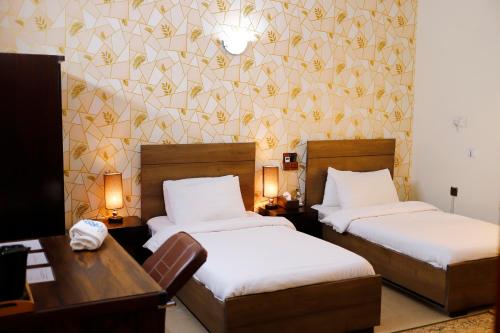 a hotel room with two beds and a desk at Waypoint Hotel in Karachi