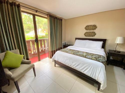 a bedroom with a bed and a chair and a window at Crosswinds Resort Condo Studio Suite in Tagaytay