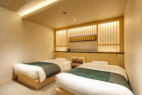 a bedroom with two beds and a window at UreshinoOnsen URESHINO YADOYA in Ureshino