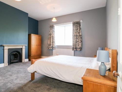 a bedroom with a white bed and a fireplace at The Cottage in Belper