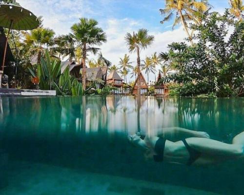 a person swimming in the water in a swimming pool at Menzel Ubud in Ubud