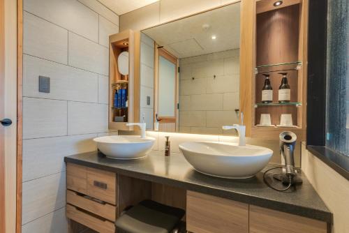 a bathroom with two white sinks and a mirror at UreshinoOnsen URESHINO YADOYA in Ureshino