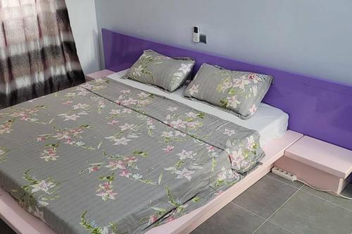 a bed with a gray blanket with flowers on it at Superbe appartement une chambre salon à Cotonou in Cotonou
