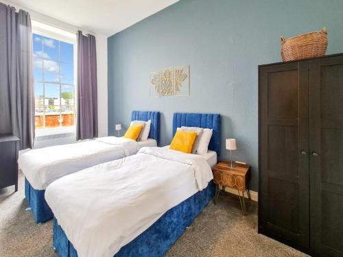 2 camas en una habitación con paredes azules en Margaret's Ground, en Cheltenham