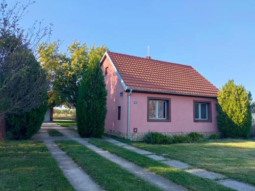 a pink house with a pathway in front of it at Little village house in Kać