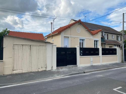 ein weißes Haus mit einem Tor und einem Zaun in der Unterkunft Maison Goussainville - Aéroport ROISSY CHARLES DE GAULLES & PARIS in Goussainville