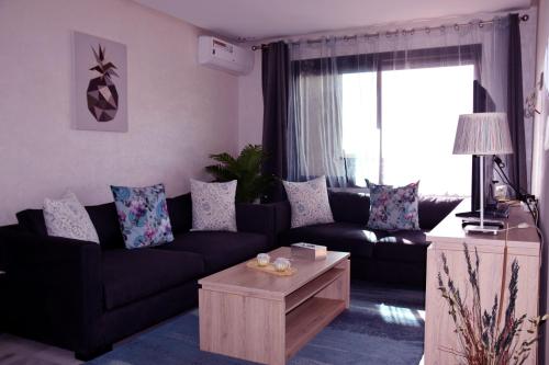 a living room with a black couch and a coffee table at AiM HOUSE in Marrakech
