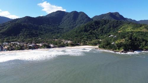 an aerial view of a beach with mountains in the background at TrevizZo Sun House Maresias in São Sebastião