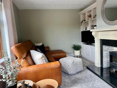 a living room with a brown leather couch and a fireplace at Sarah’s cottage in Newry