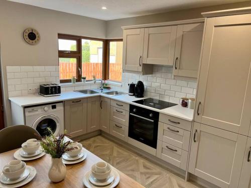 a kitchen with white cabinets and a table with dishes at Sarah’s cottage in Newry