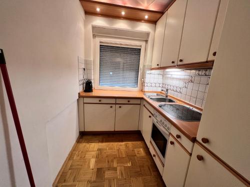 eine kleine Küche mit weißen Schränken und einem Fenster in der Unterkunft Life Apartment in Essen