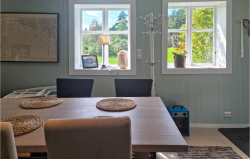 a dining room with a wooden table and two windows at 4 Bedroom Amazing Home In Farsund in Farsund