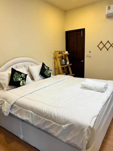 a large white bed with black pillows on it at Baan Pranai In Pai in Pai