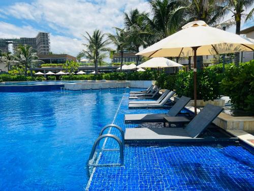 a swimming pool with lounge chairs and an umbrella at Luxury villa trong Whyndham garden Cam Ranh in Nha Trang