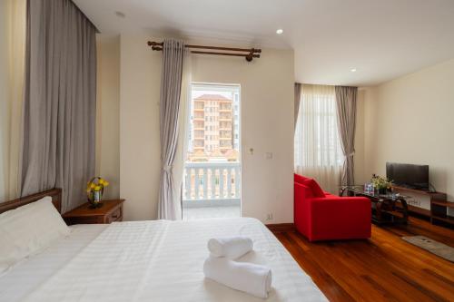 a bedroom with a white bed and a red chair at E&V Apartment in Phnom Penh