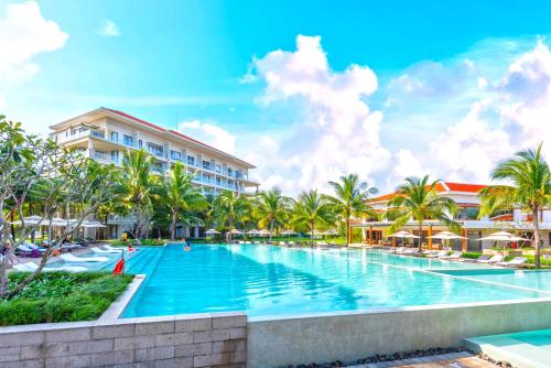 a swimming pool at a resort with palm trees at Danang Amazing Ocean Beach Resort in Danang