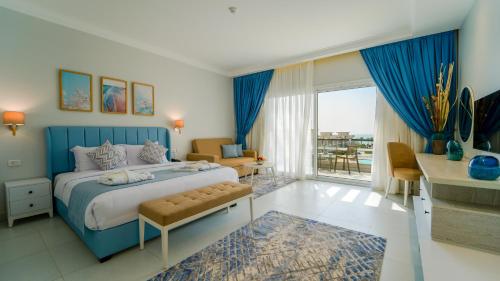 ein Schlafzimmer mit einem blauen Bett und einem Balkon in der Unterkunft SeaVille Beach Hotel by Elite Hotels & Resorts in Ain Suchna