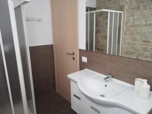y baño con lavabo blanco y espejo. en A Casa Grelletto Gubbio, en Gubbio