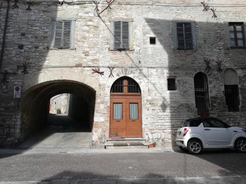 un coche blanco estacionado frente a un edificio con una puerta de madera en A Casa Grelletto Gubbio, en Gubbio