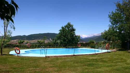 a swimming pool in a field with mountains in the background at Camping Aín Jaca in Jaca