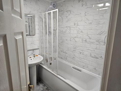 uma casa de banho branca com um lavatório, uma banheira e um WC. em Snug - Colquhoun Square Apartment em Helensburgh