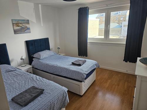 um quarto com 2 camas e uma janela em Snug - Colquhoun Square Apartment em Helensburgh