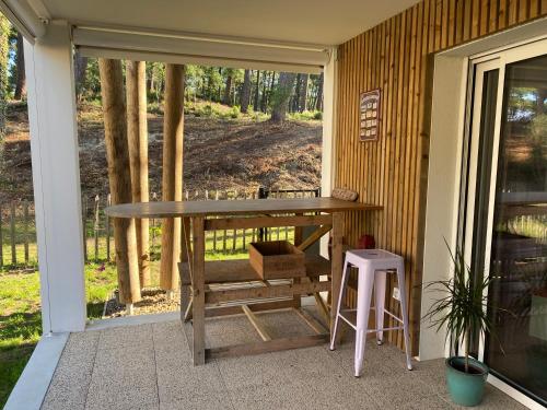 une véranda avec une table en bois et un tabouret dans l'établissement Ocean Chill, à Seignosse