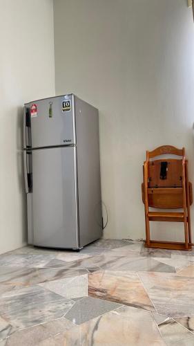 a refrigerator in a corner of a room with a chair at 515 Nana’s Homes in Sekinchan in Sekincan