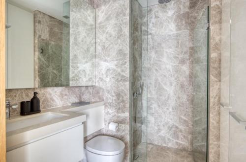 a bathroom with a toilet and a glass shower at Spectacular 1BR Apartment in Singapore! in Singapore