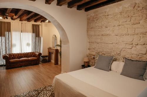 1 dormitorio con cama y pared de piedra en Astuto Boutique Jerez - Adults Only, en Jerez de la Frontera