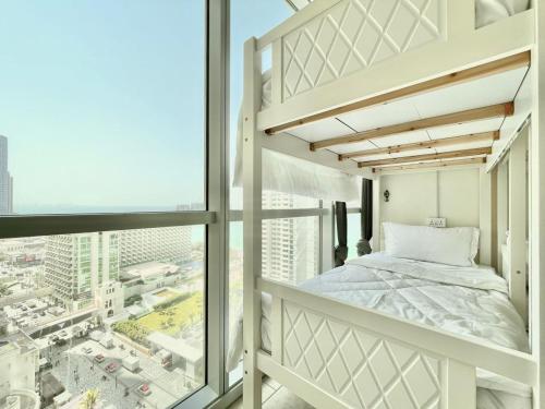 AR Holiday Home JBR في دبي: غرفة نوم مع سرير بطابقين ونوافذ كبيرة