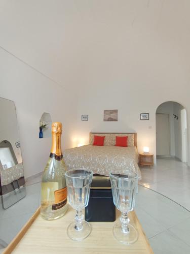 uma garrafa de vinho e dois copos numa mesa com uma cama em L'Archetto romantic suite in the center of Anacapri em Anacapri