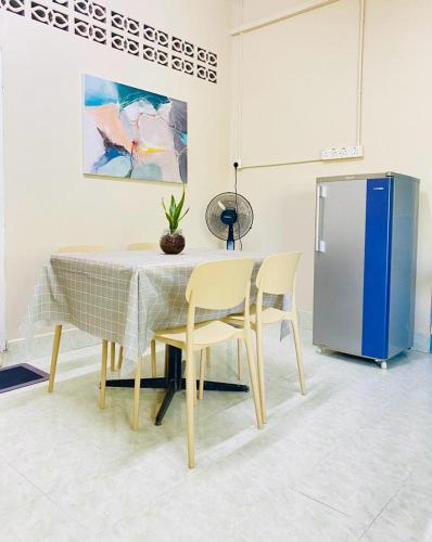 a table with two chairs and a refrigerator in a room at SOFEA HOMESTAY in Pantai Cenang