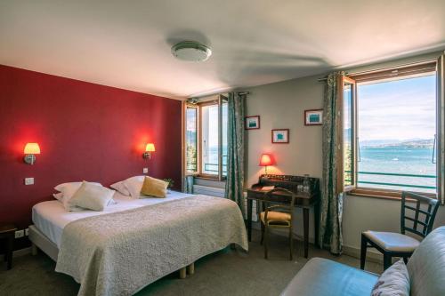 Cette chambre comprend 2 lits et un mur rouge. dans l'établissement Hôtel de la Plage, à Excenevex