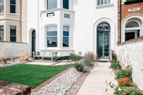 a white house with a bench in the yard at Avondale, Southwold in Southwold