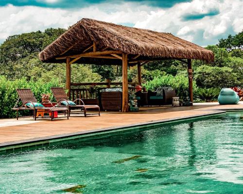 a deck with chairs and a pavilion next to a swimming pool at Espaço Vento Solar in São Roque