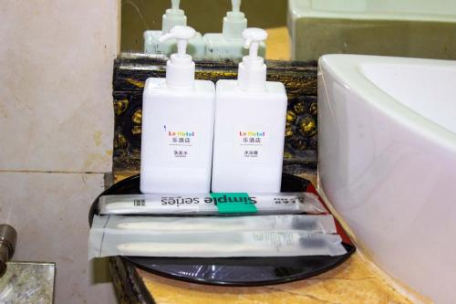 two bottles of soap on a counter next to a sink at Le Hotel Hotel Phnom Penh in Phnom Penh